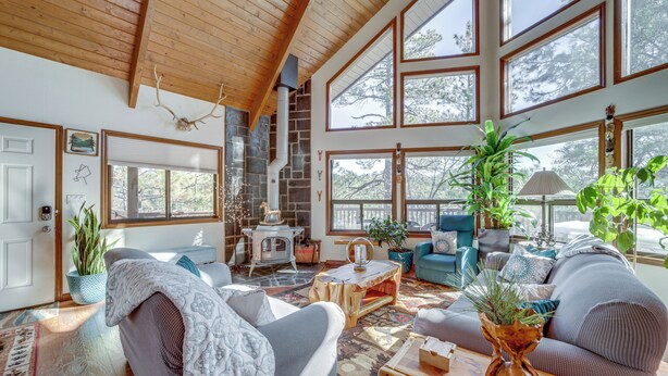 A spacious living room with a fireplace, large windows, and comfortable seating areas. - Deck & Scenic Views: Munds Park A-frame Cabin (Munds Park)