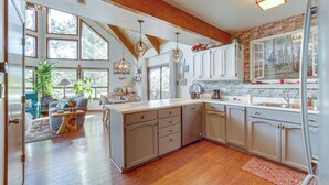 A spacious kitchen with wooden beams, large windows, and a central island. - Deck & Scenic Views: Munds Park A-frame Cabin (Munds Park)