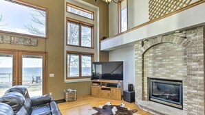 A spacious living room with a large TV, fireplace, and leather sofa.