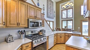 A kitchen with wooden cabinets, stainless steel appliances, and a large window.
