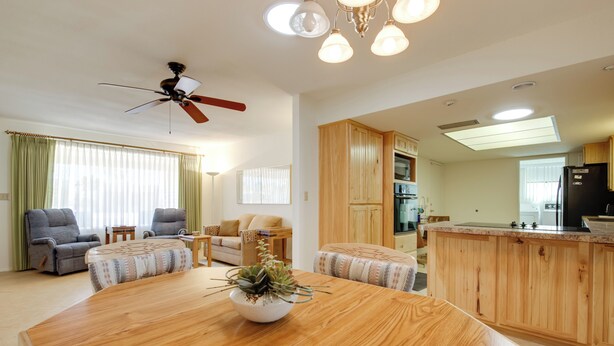 A spacious living room with a wooden dining table, two armchairs, a sofa, and a ceiling fan. - Patio & Mtn Views: 55 + Apache Junction Home! (Apache Junction)