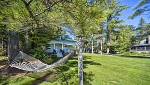 A hammock between trees, a house with a porch, and a well-maintained lawn. - Fire Pit & Beach: Lake Pleasant Home w/ Views (Speculator)