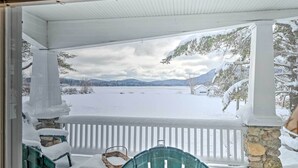 A covered porch with a view of a snowy landscape and mountains. - Fire Pit & Beach: Lake Pleasant Home w/ Views (Speculator)