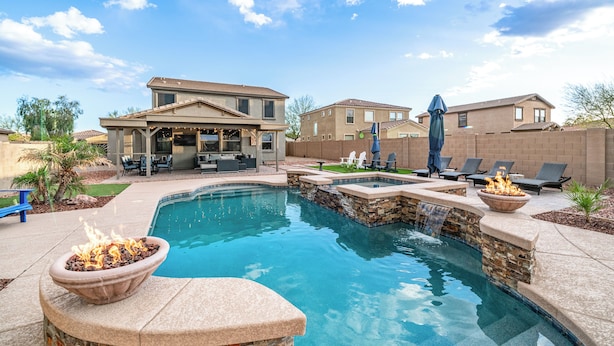 A backyard with a swimming pool, a fire pit, and outdoor furniture. - Pool & Patio: Family-friendly Goodyear Home! (Goodyear)