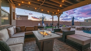 An outdoor patio with a fire pit, seating area, and a pool. - Pool & Patio: Family-friendly Goodyear Home! (Goodyear)