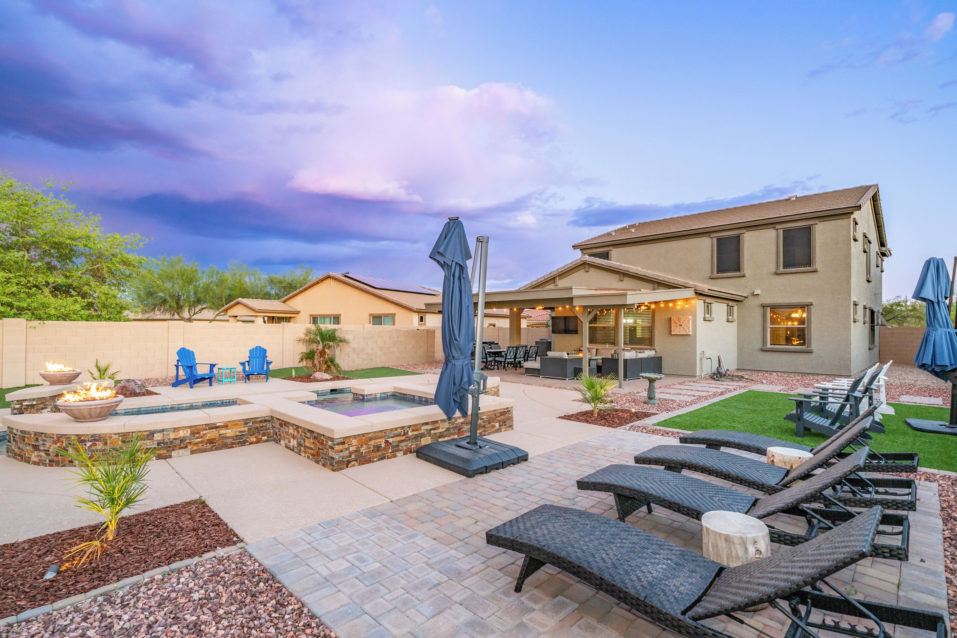 A patio area with lounge chairs, a fire pit, and a hot tub.