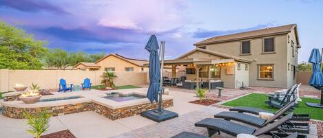 A patio area with lounge chairs, a fire pit, and a hot tub.