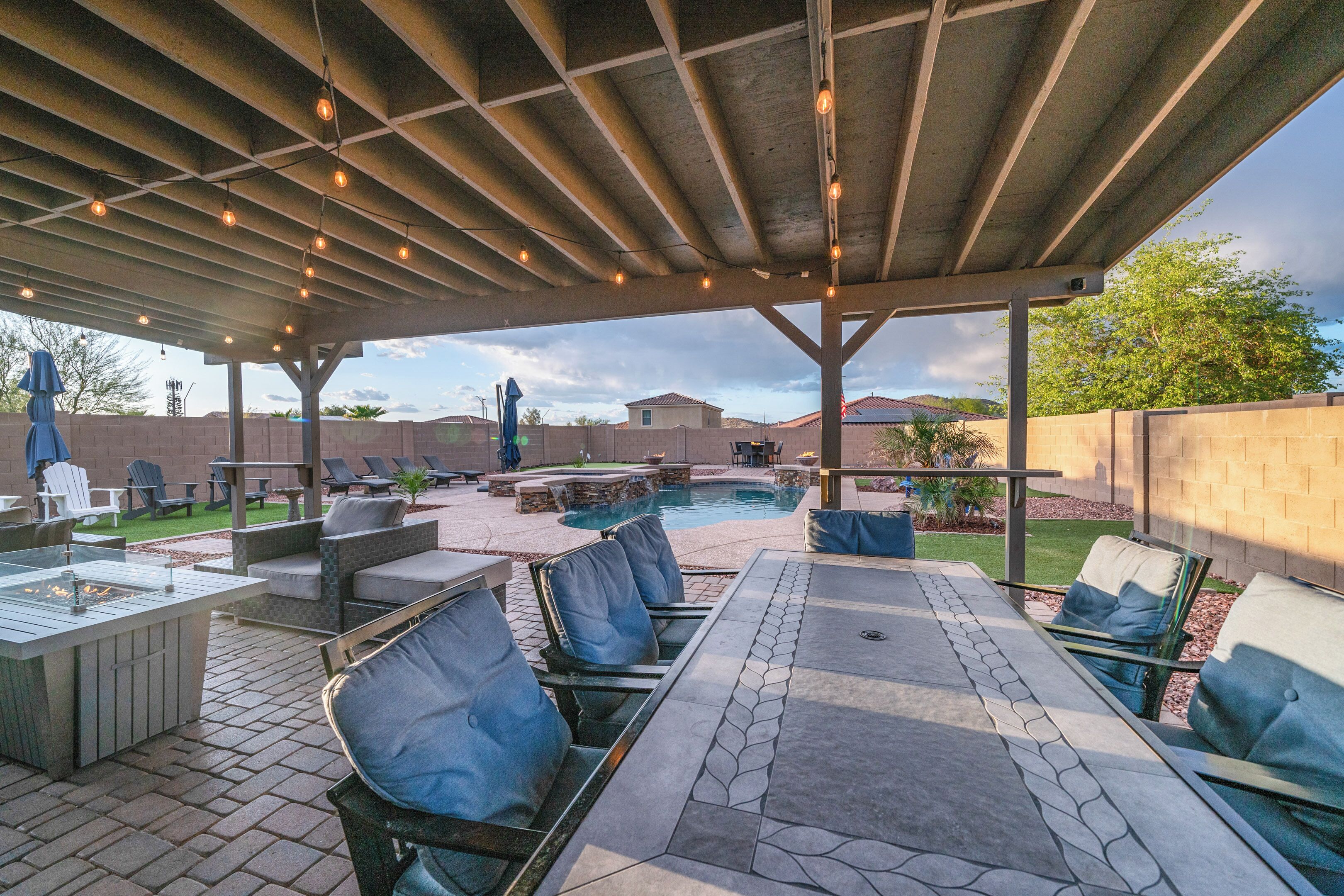 An outdoor patio with a pool, lounge chairs, and a covered seating area.