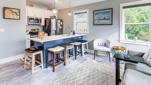 A modern kitchen with a central island, bar stools, a refrigerator, and a microwave. - Walk to Dtwn: Charlevoix Condo w/ Fireplace (Charlevoix)