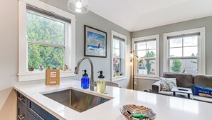 A kitchen with a large island, a double sink, and a window with a view of trees. - Walk to Dtwn: Charlevoix Condo w/ Fireplace (Charlevoix)