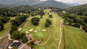 A golf course with multiple holes, surrounded by dense forest and hills. - Cozy Mountain Home at Rumbling Bald Resort! (Lake Lure)