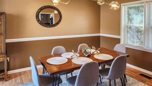 A dining area with a wooden table, six chairs, and a chandelier. - Cozy Mountain Home at Rumbling Bald Resort! (Lake Lure)