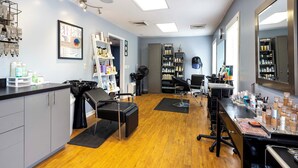 A salon with a wooden floor, black salon chairs, shelves with hair products, and a large mirror. - Cozy Mountain Home at Rumbling Bald Resort! (Lake Lure)