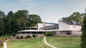 A modern building with a stone facade, large windows, and a covered patio area. - Cozy Mountain Home at Rumbling Bald Resort! (Lake Lure)