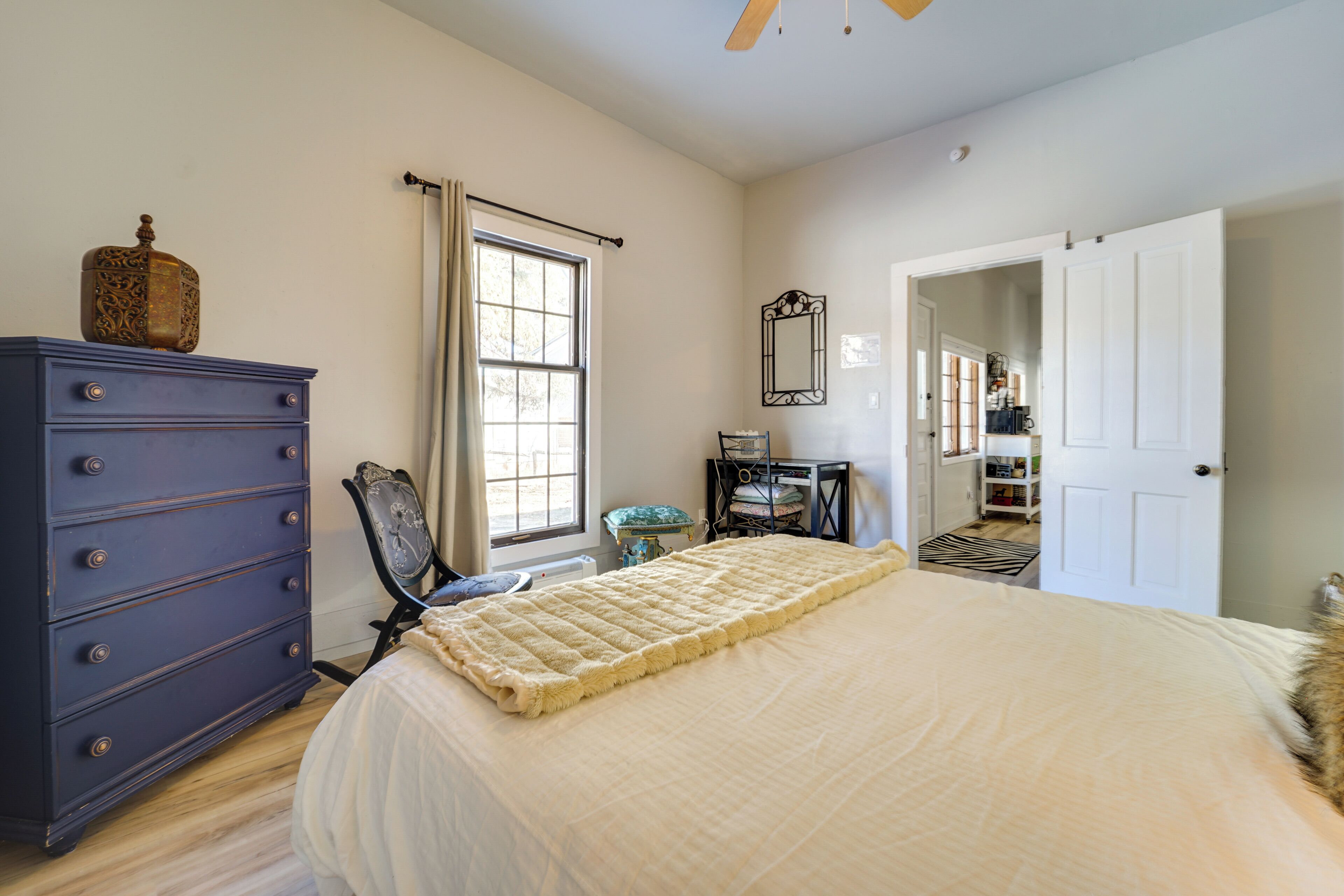 A bedroom with a bed, dresser, and a window.