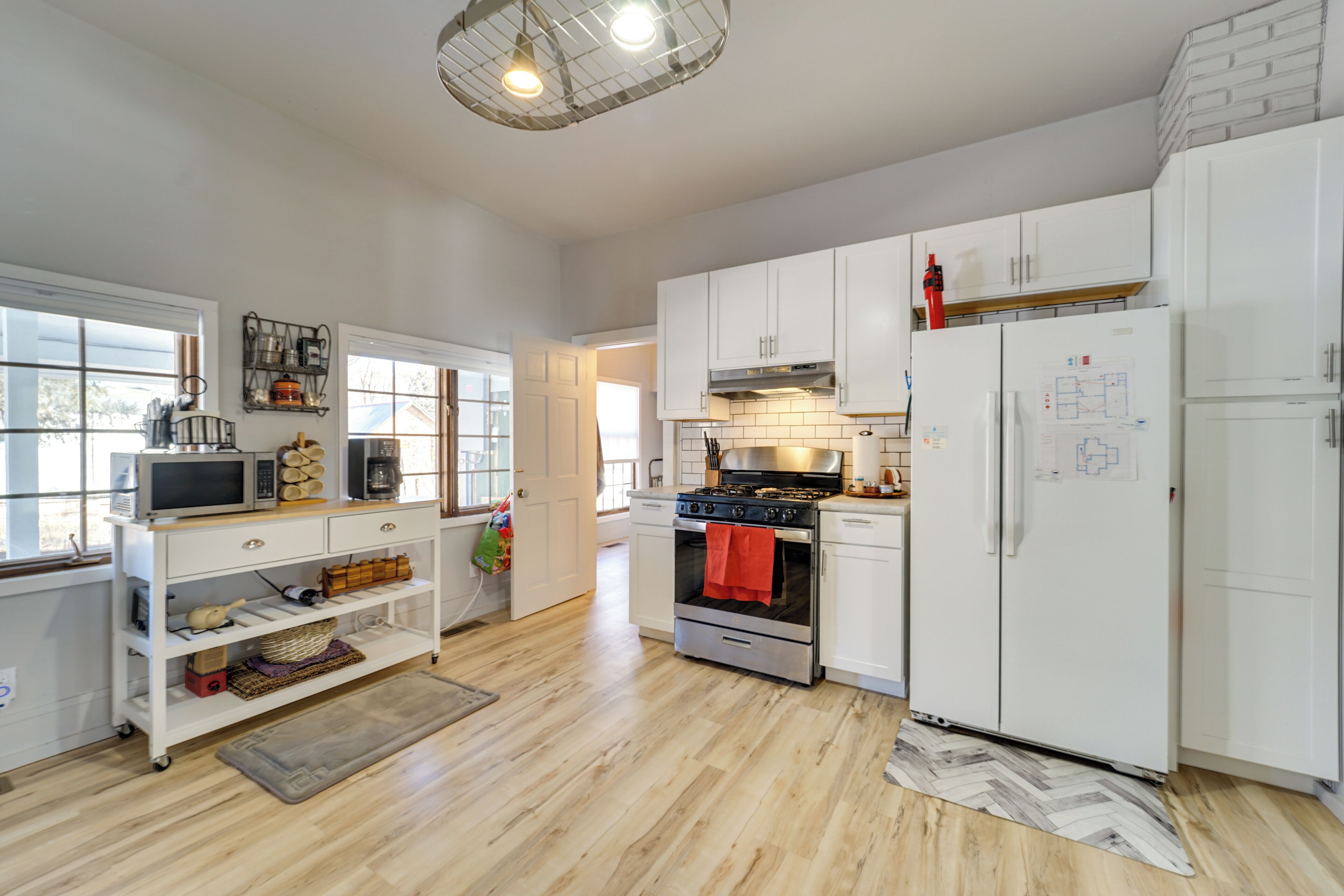 A modern kitchen with white cabinets, stainless steel appliances, and a herringbone-patterned rug.