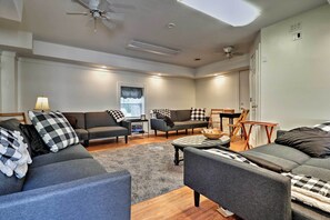 A modern living room with grey sofas, a coffee table, and a dining area with a table and chairs.