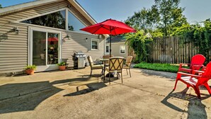 Eine Terrasse mit Tisch, Stühlen, einem roten Sonnenschirm und Topfpflanzen.
