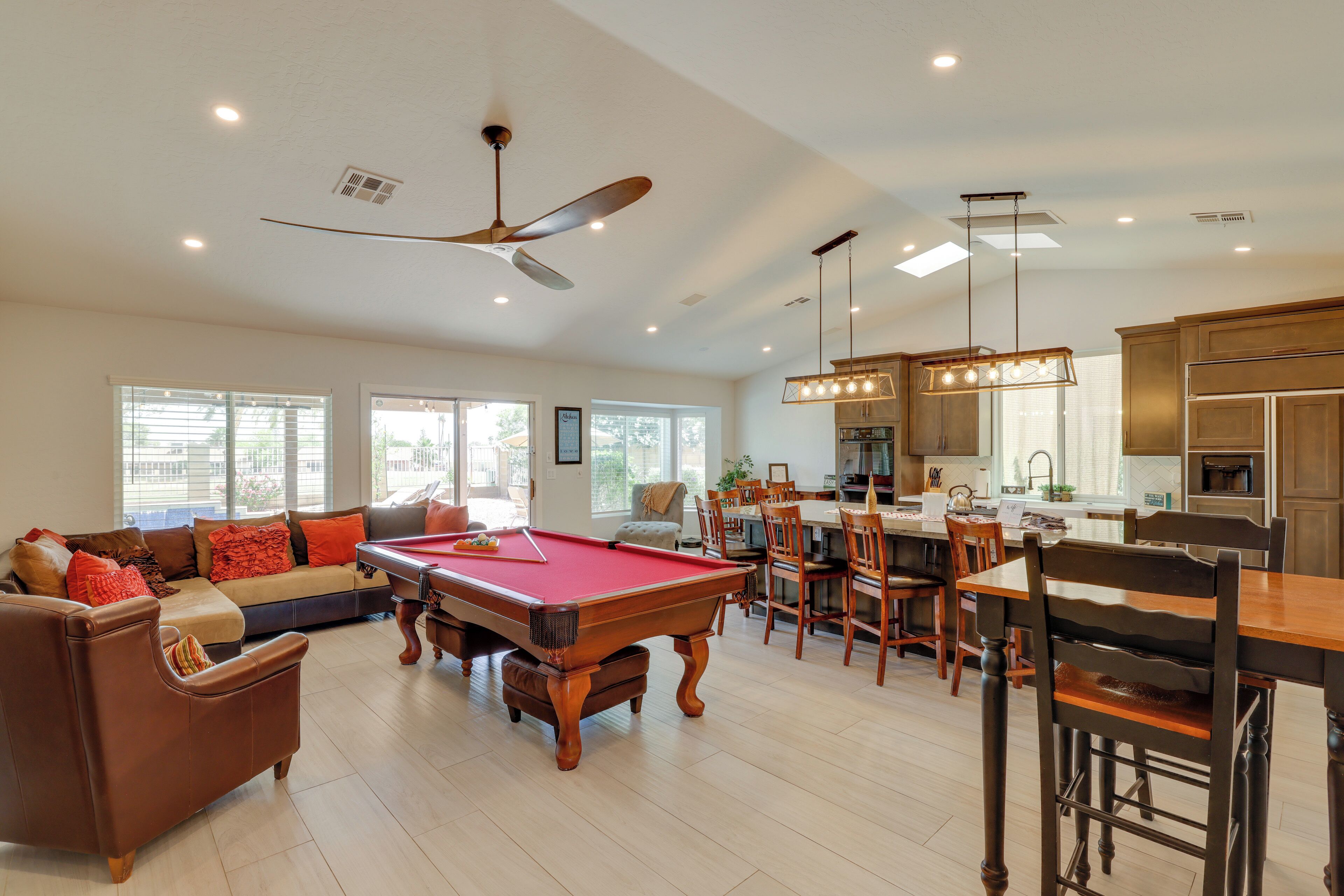 A spacious living room with a pool table, a sofa, and a dining area with wooden chairs and a table.