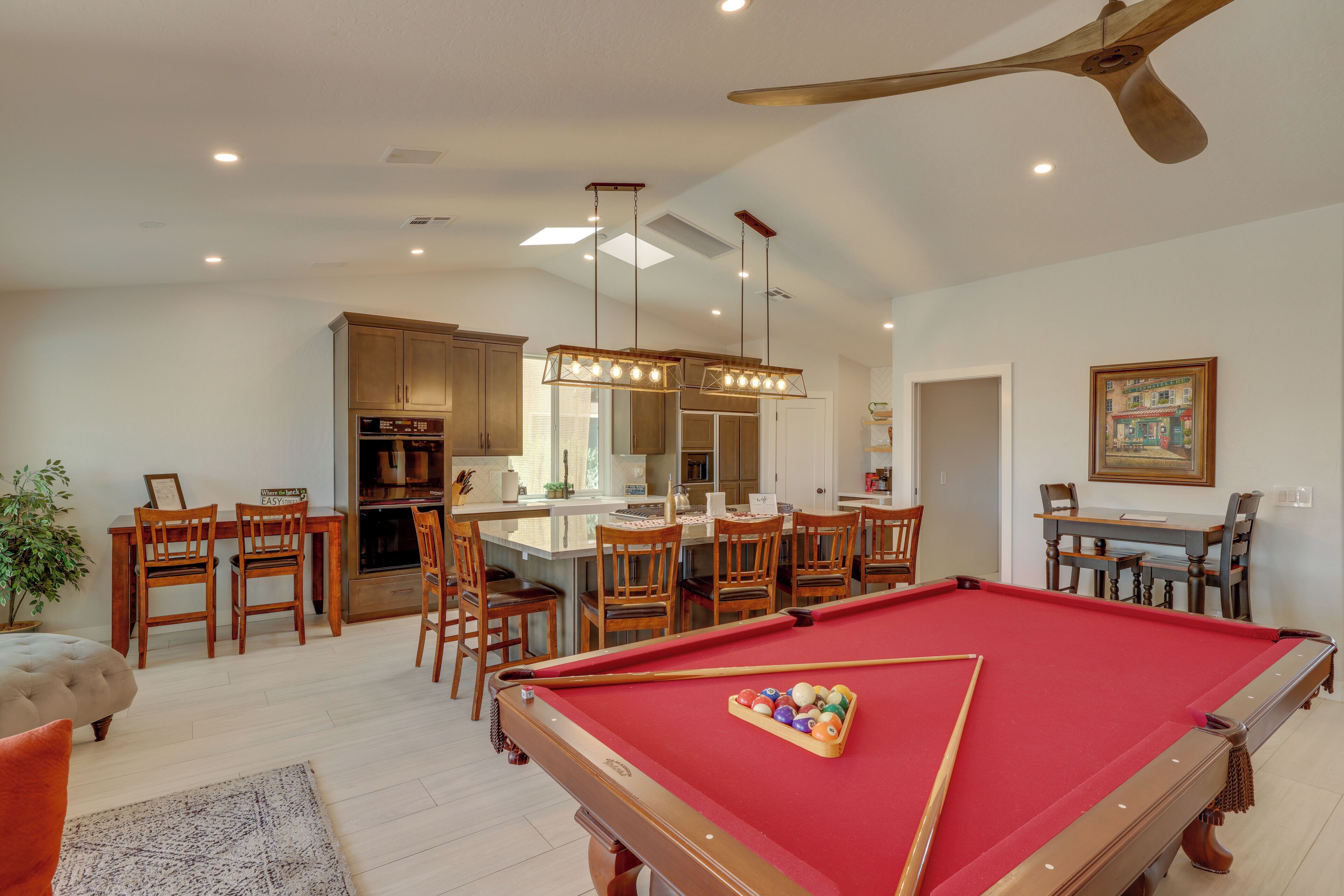 A spacious living area with a pool table, dining area, and kitchen.