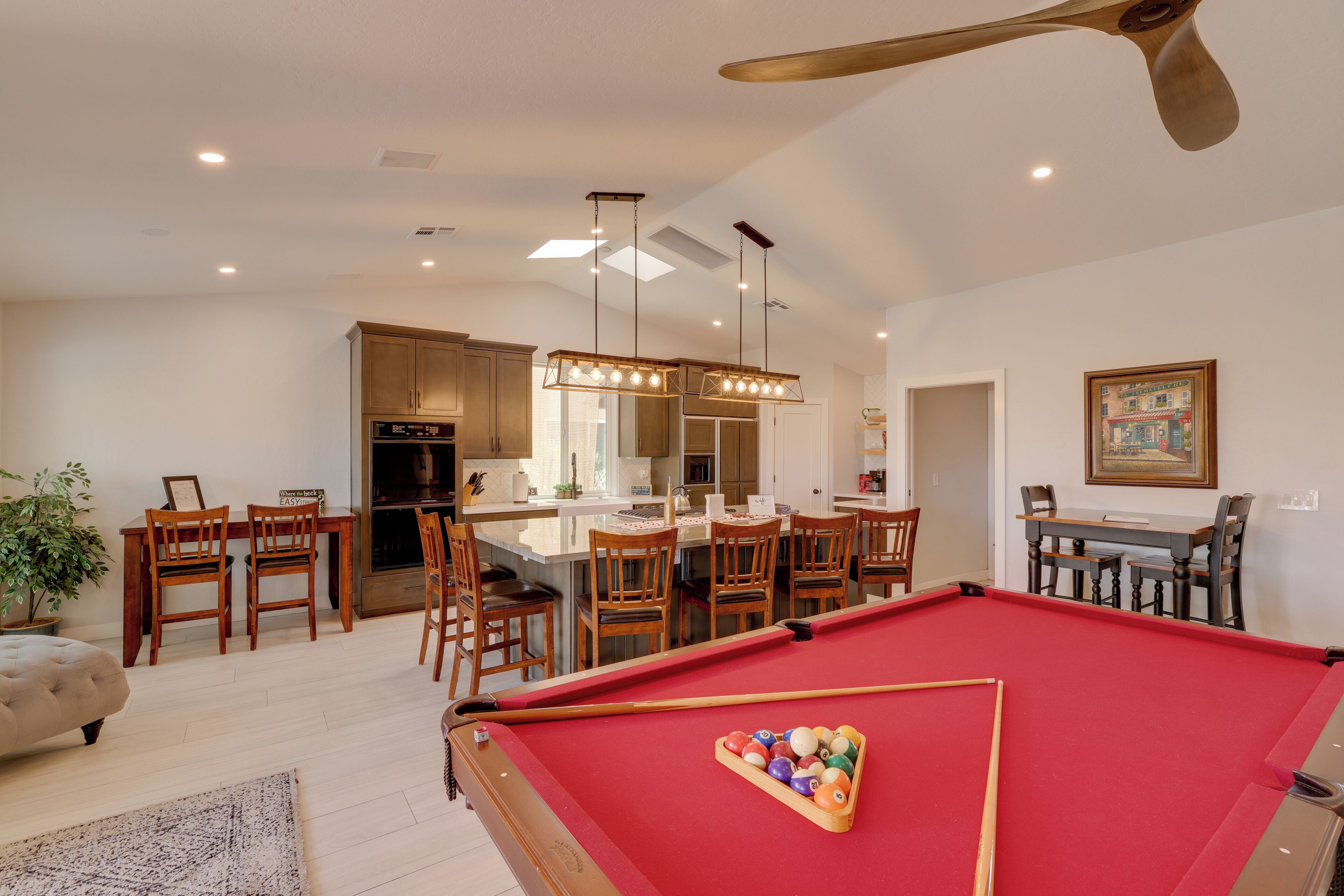 A pool table in a well-lit room with wooden furniture and a ceiling fan.
