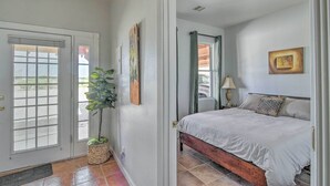 Une chambre à coucher avec un lit, une porte, une fenêtre et une plante en pot.