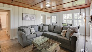 A living room with a sectional sofa, a glass coffee table, wooden ceiling, and large windows. - Chic Columbia Home < 2 Mi to Historic Square! (Columbia)