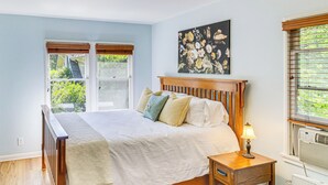 A bedroom with a wooden bed, a nightstand with a lamp, a window with blinds, and a wall-mounted artwork. - Central South Pasadena Apt, 3 Mi to Rose Bowl (South Pasadena)