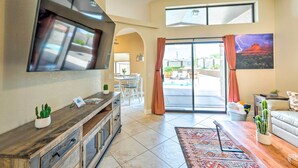 A modern living room with a flat-screen TV, a dining area, and a view of the outdoors. - Havasu Vacation Rental w/ Private Pool & Hot Tub! (Lake Havasu City)