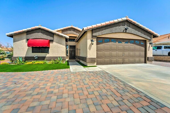 A residential house with a garage, a red awning, and a paved driveway.