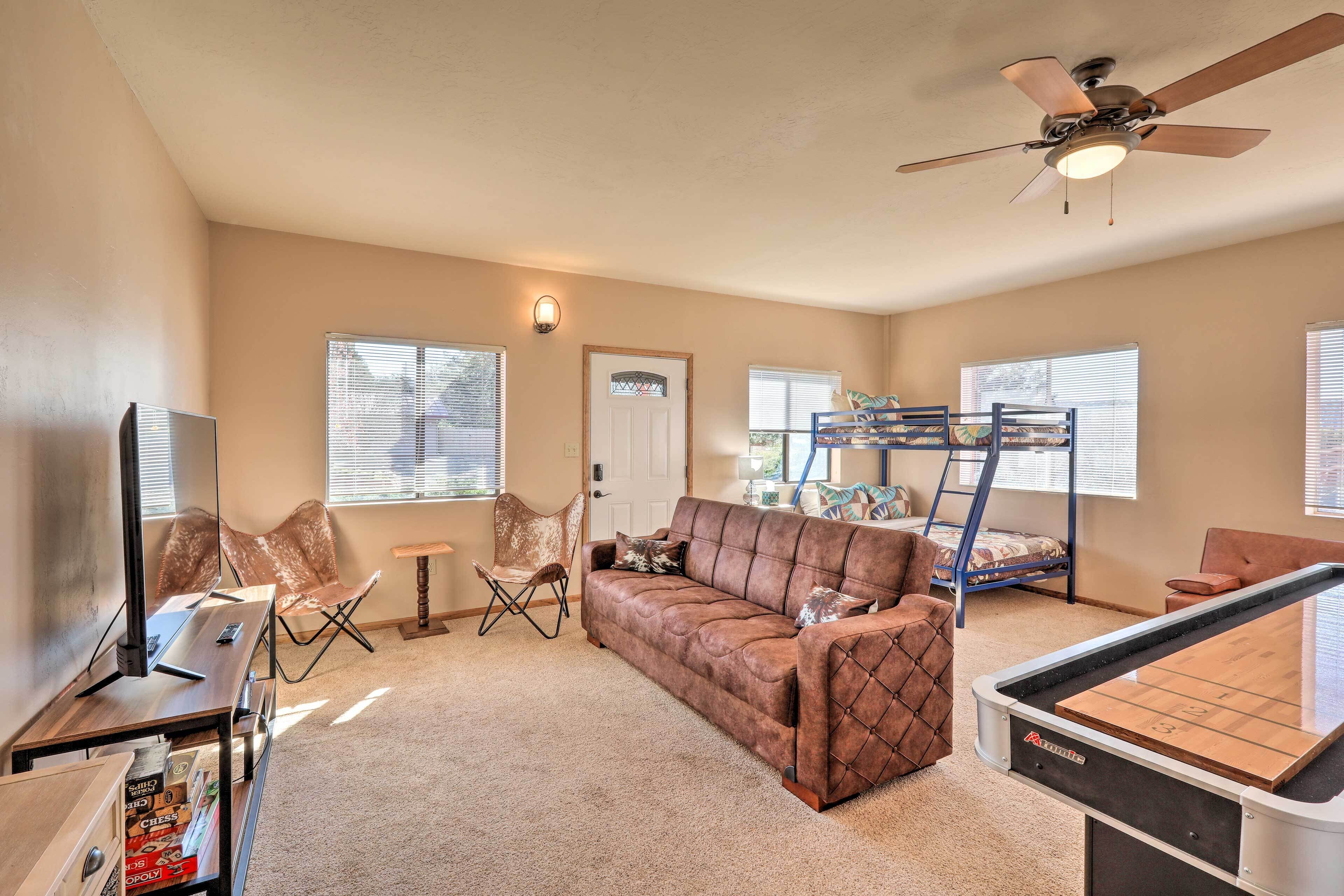 A living room with a brown sofa, a coffee table, a TV, and a ceiling fan.