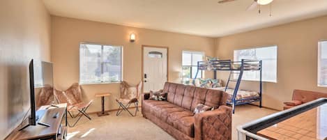 A living room with a brown sofa, a coffee table, a TV, and a ceiling fan.