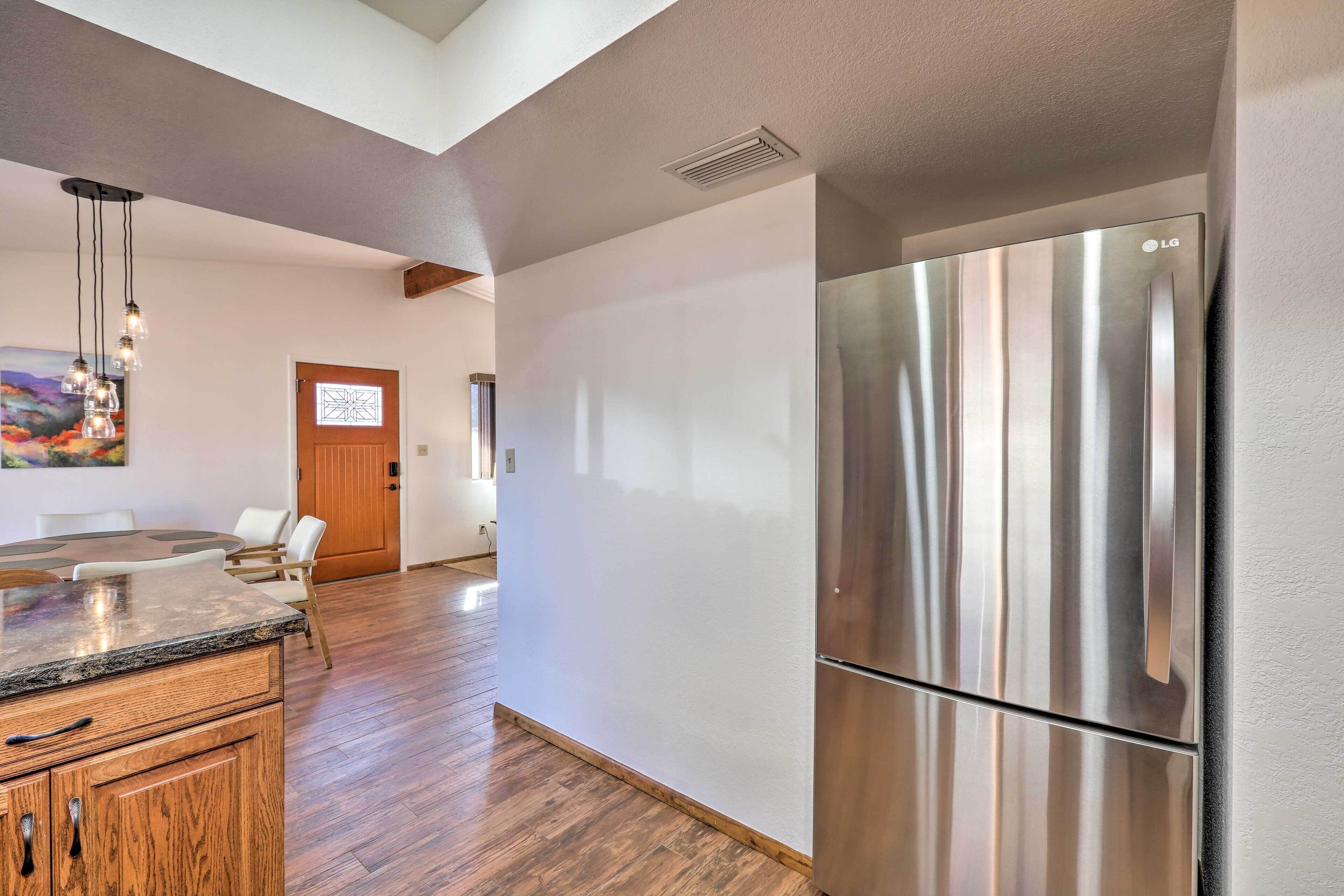A modern kitchen with a stainless steel refrigerator, wooden cabinets, and a dining area with a table and chairs.