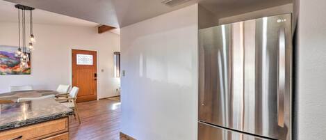 A modern kitchen with a stainless steel refrigerator, wooden cabinets, and a dining area with a table and chairs.