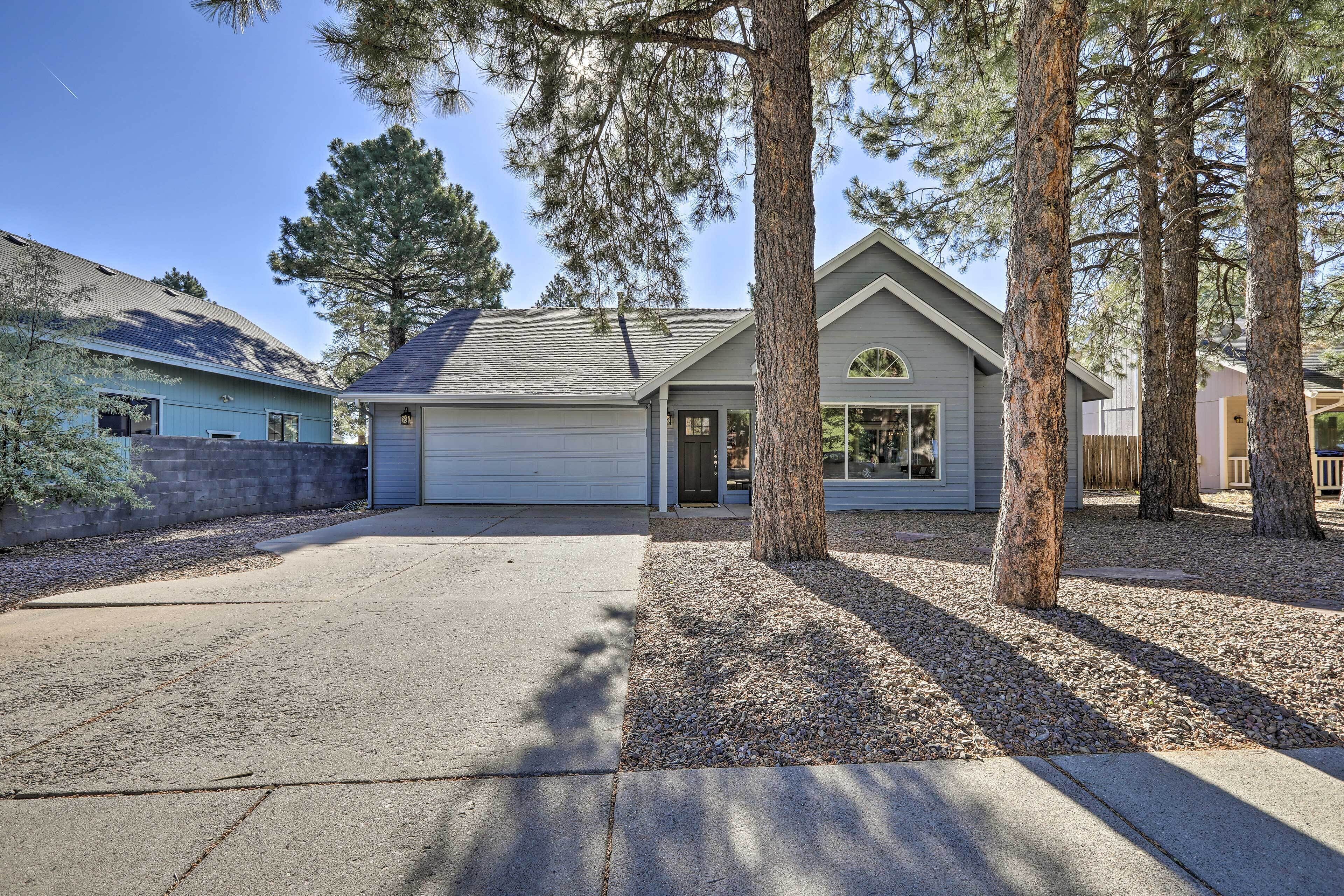A residential property with a garage, a driveway, and a well-maintained lawn with trees.