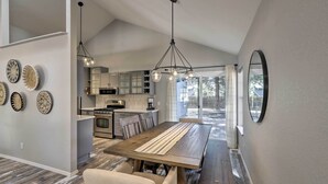 A modern kitchen with a central island, a dining area with a wooden table and chairs, and a large mirror on the wall. - Modern Flagstaff Retreat ~ 4 Mi to Downtown! (Flagstaff)