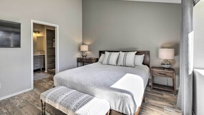 A bedroom with a large bed, bedside tables with lamps, a bench, and a walk-in closet. - Modern Flagstaff Retreat ~ 4 Mi to Downtown! (Flagstaff)