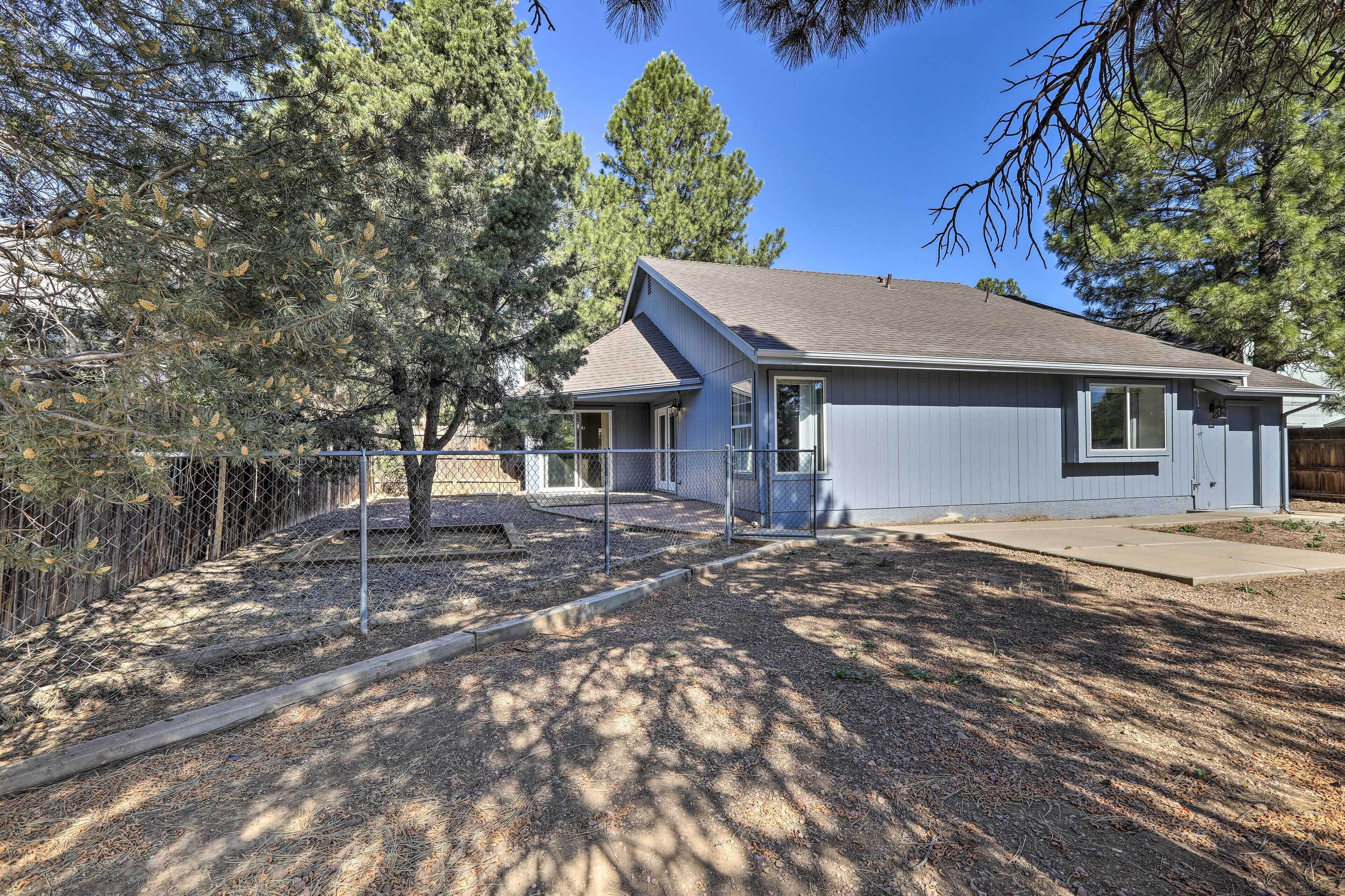 A single-story house with a grey roof, a front porch, and a fenced yard.