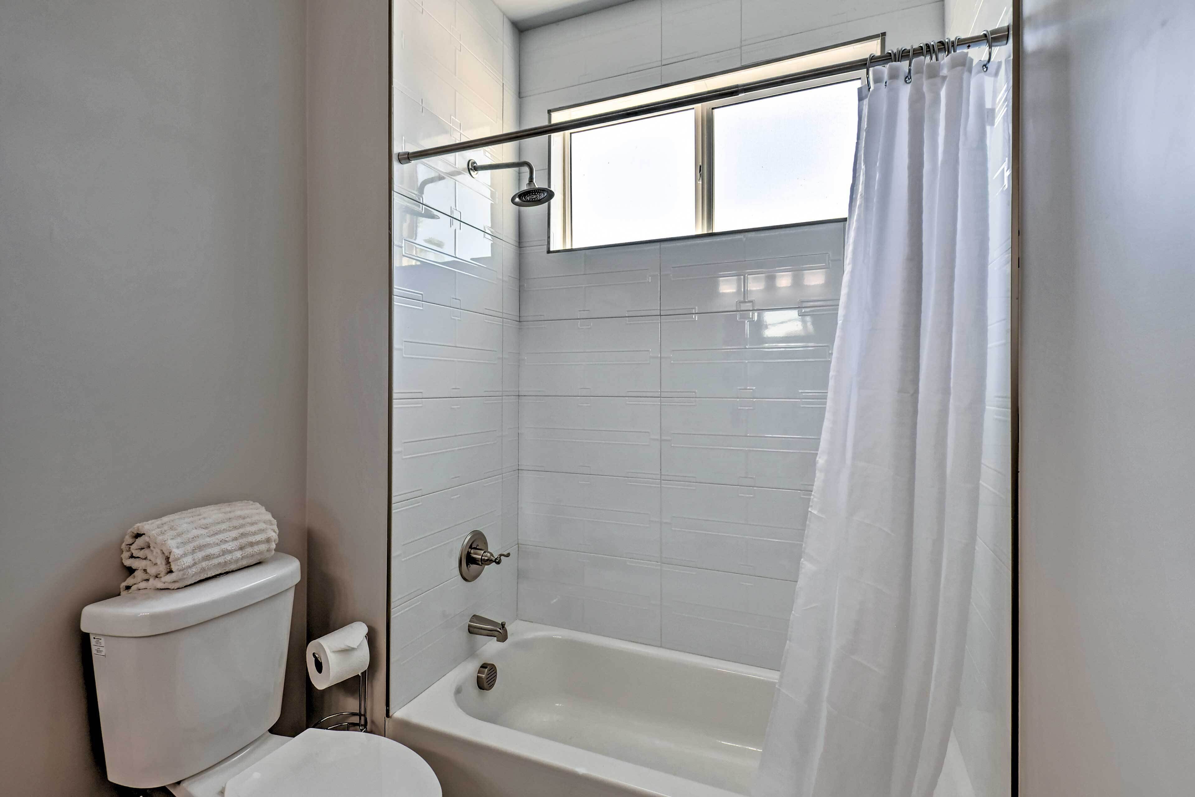 A bathroom with a bathtub, toilet, and a shower curtain.