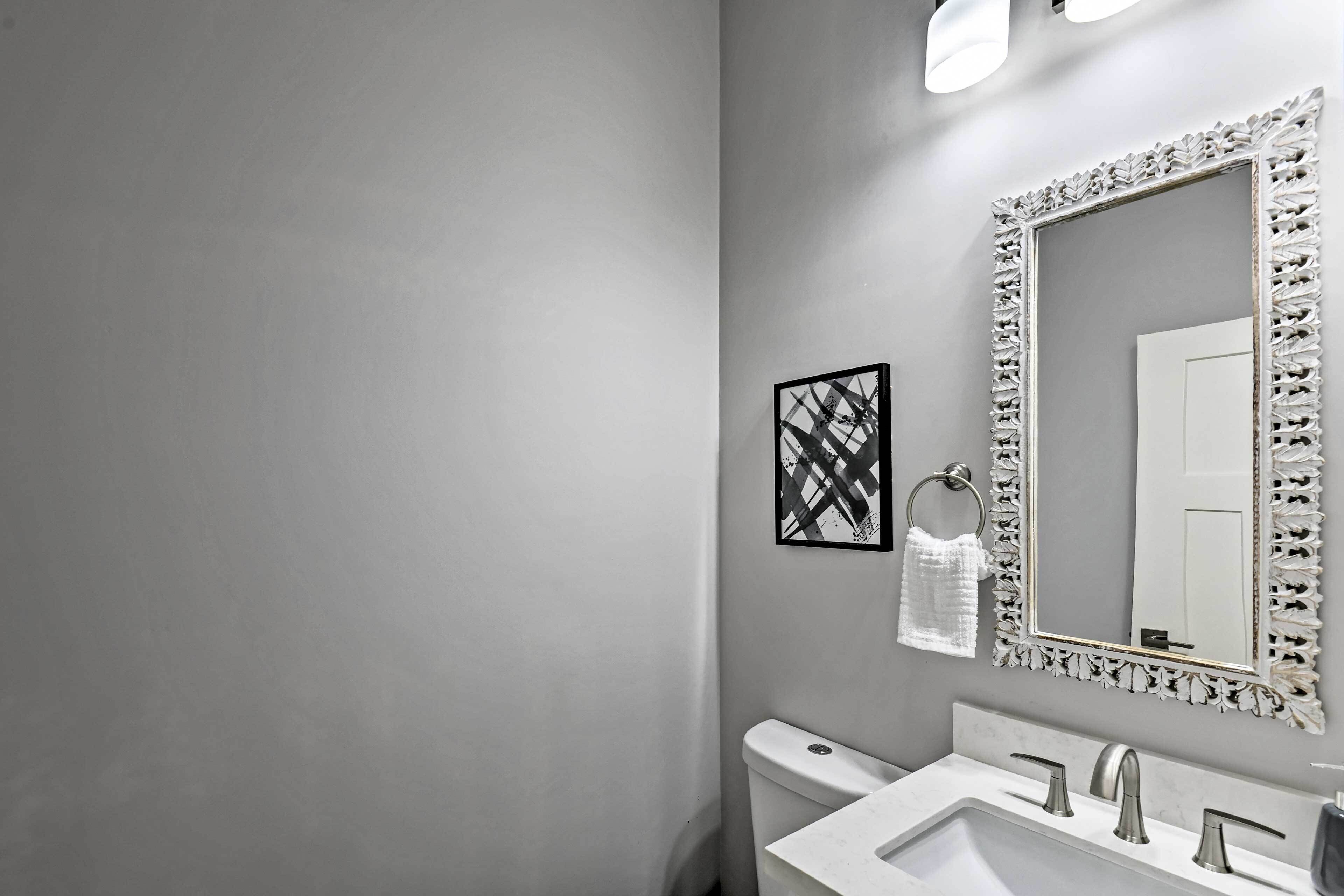 A bathroom with a white sink, a toilet, and a large mirror with a decorative frame.