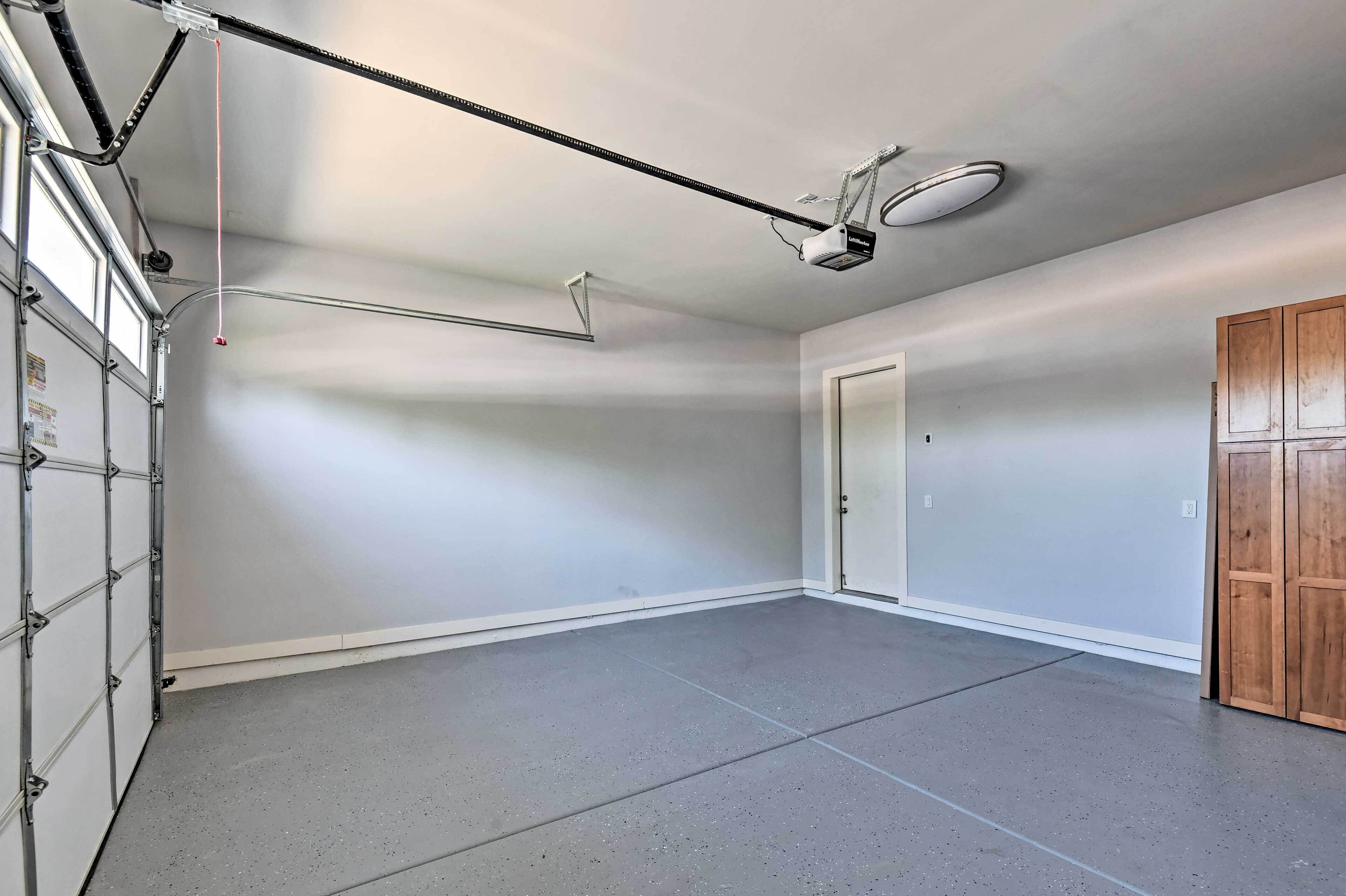 Een garage met een betonvloer, een aan het plafond bevestigde projecteerder en een deur.
