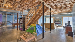 A spacious room with a loft area, a staircase, a tent, and a foosball table.