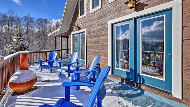 A wooden building with a covered deck, blue Adirondack chairs, and a snow-covered ground.