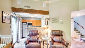 A spacious living area with leather armchairs, a small table, and a kitchen in the background. - Second-floor Condo w/ Community Pool Access! (Nellysford)