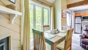 A dining area with a wooden table, chairs, and a view of greenery outside. - Second-floor Condo w/ Community Pool Access! (Nellysford)