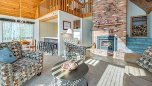 A cozy living room with patterned furniture, a fireplace, and a wooden balcony.