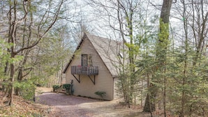 A cabin with a gravel driveway, surrounded by trees.