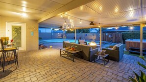 Ein überdachter Patio-Bereich mit Gartenmöbeln, Lichterketten und einem Whirlpool.