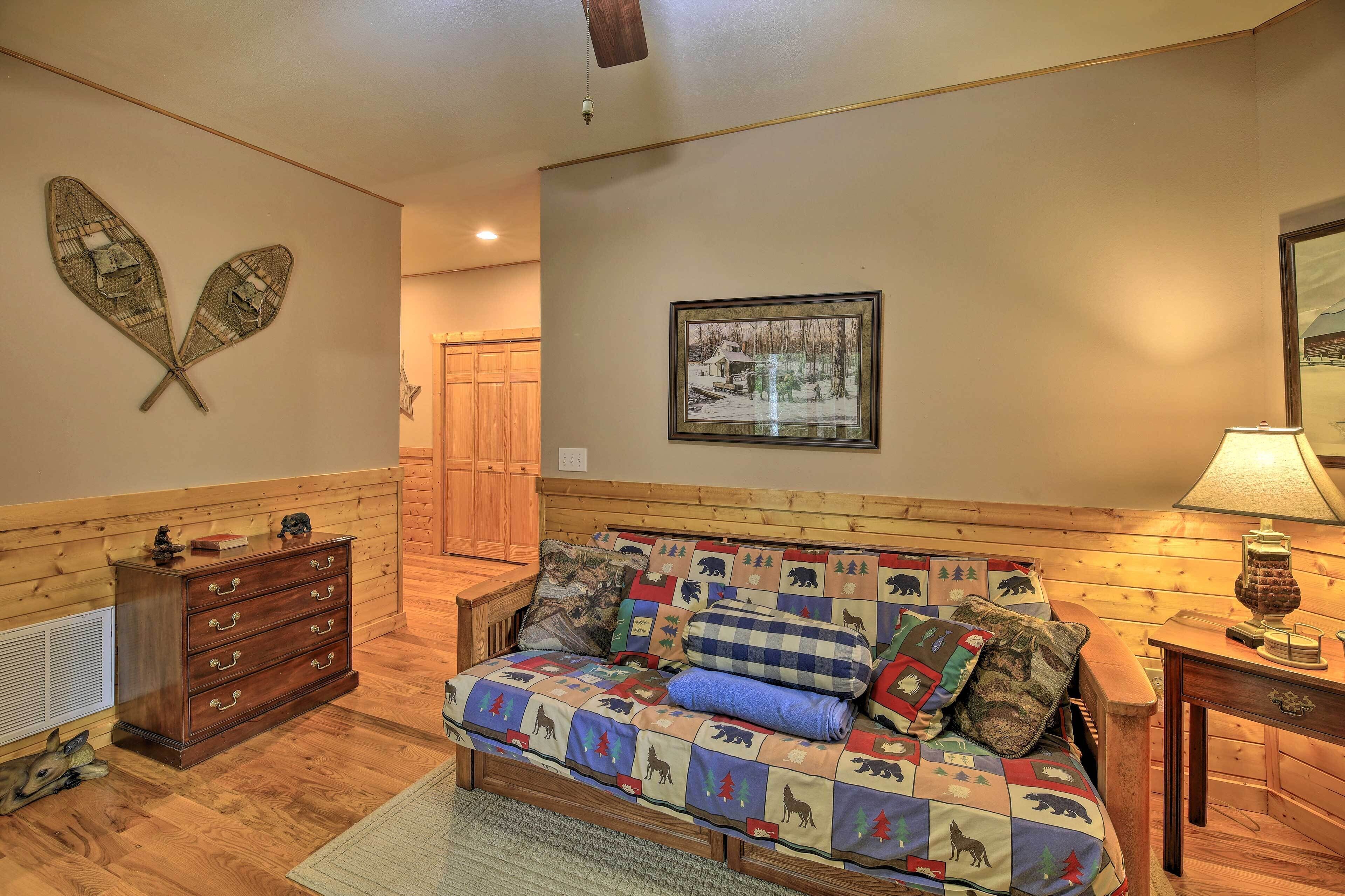 A cozy room with a wooden floor, a wooden bench, a quilted sofa, a wooden dresser, and a framed picture on the wall.