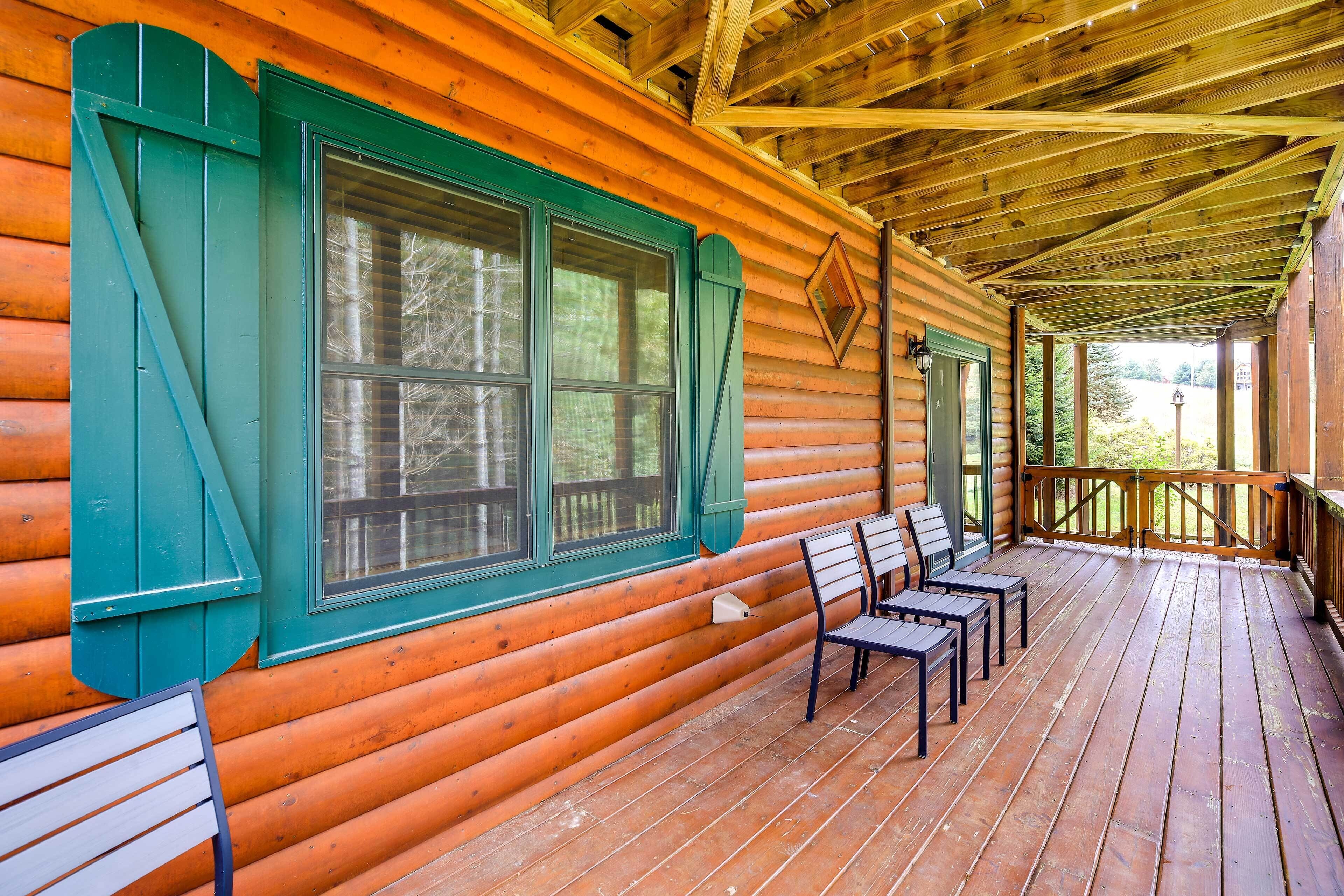 A log cabin with a porch, two chairs, and a window with shutters.